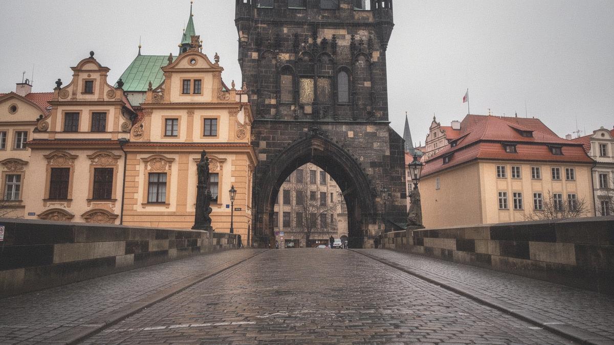 Baroque gable and bridge tower above a cobbled street in the Lesser Town of Prague